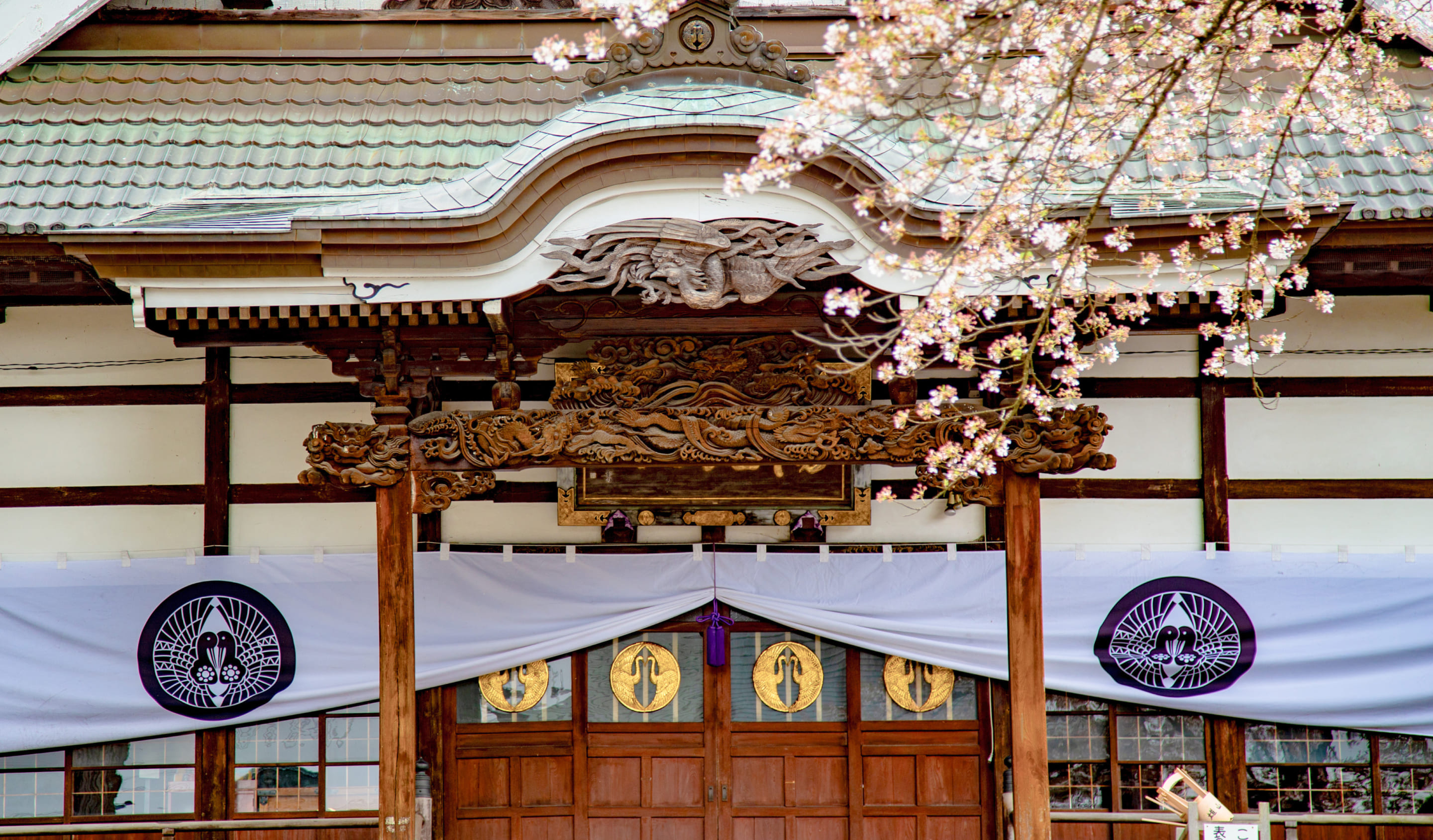 桜越しに見える雄山寺の美しい木造の装飾